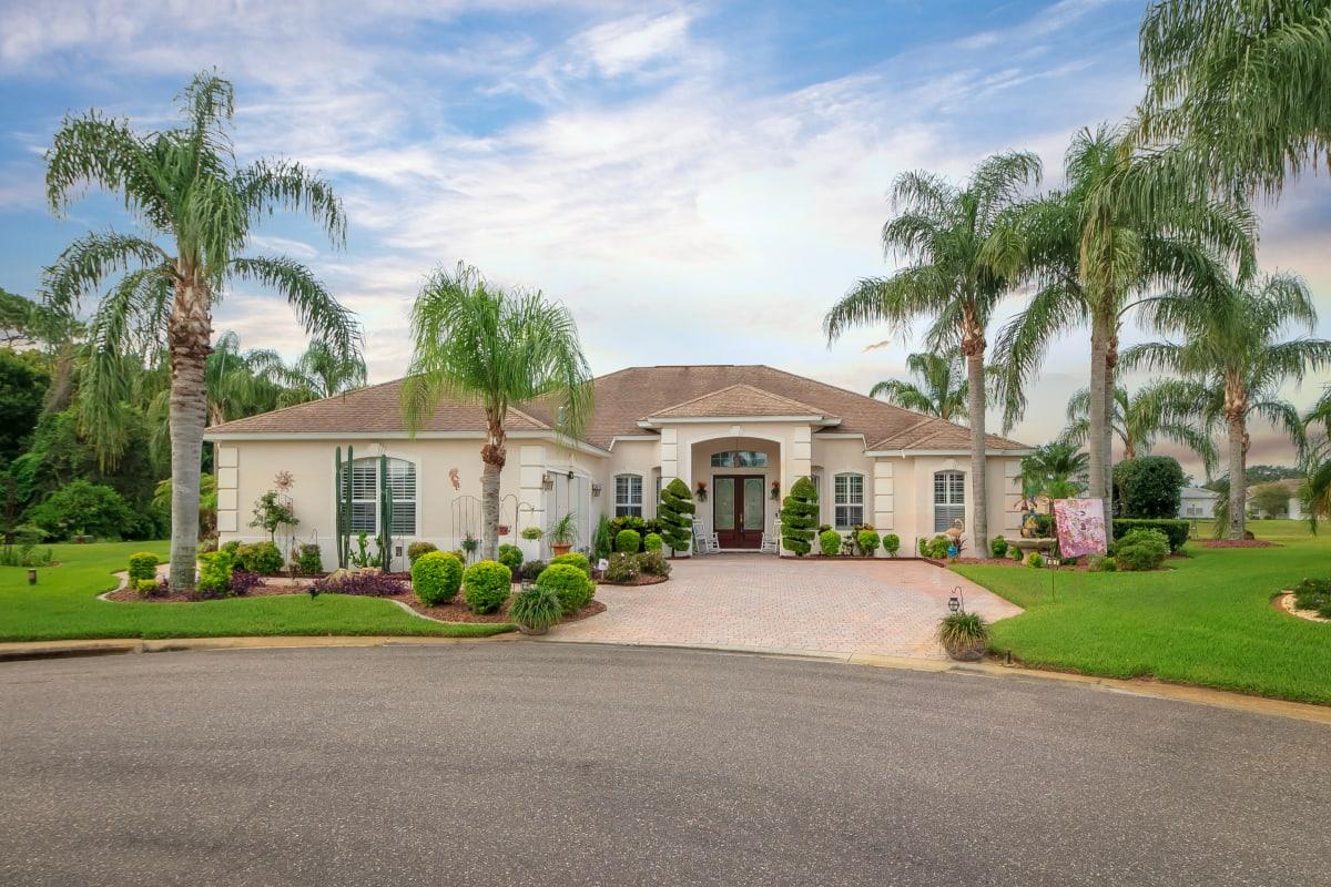 Florida-style home exterior with brick driveway and palm trees