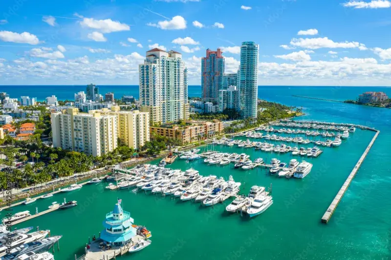Aerial view of South Florida marina with boats, luxury condos, and turquoise water